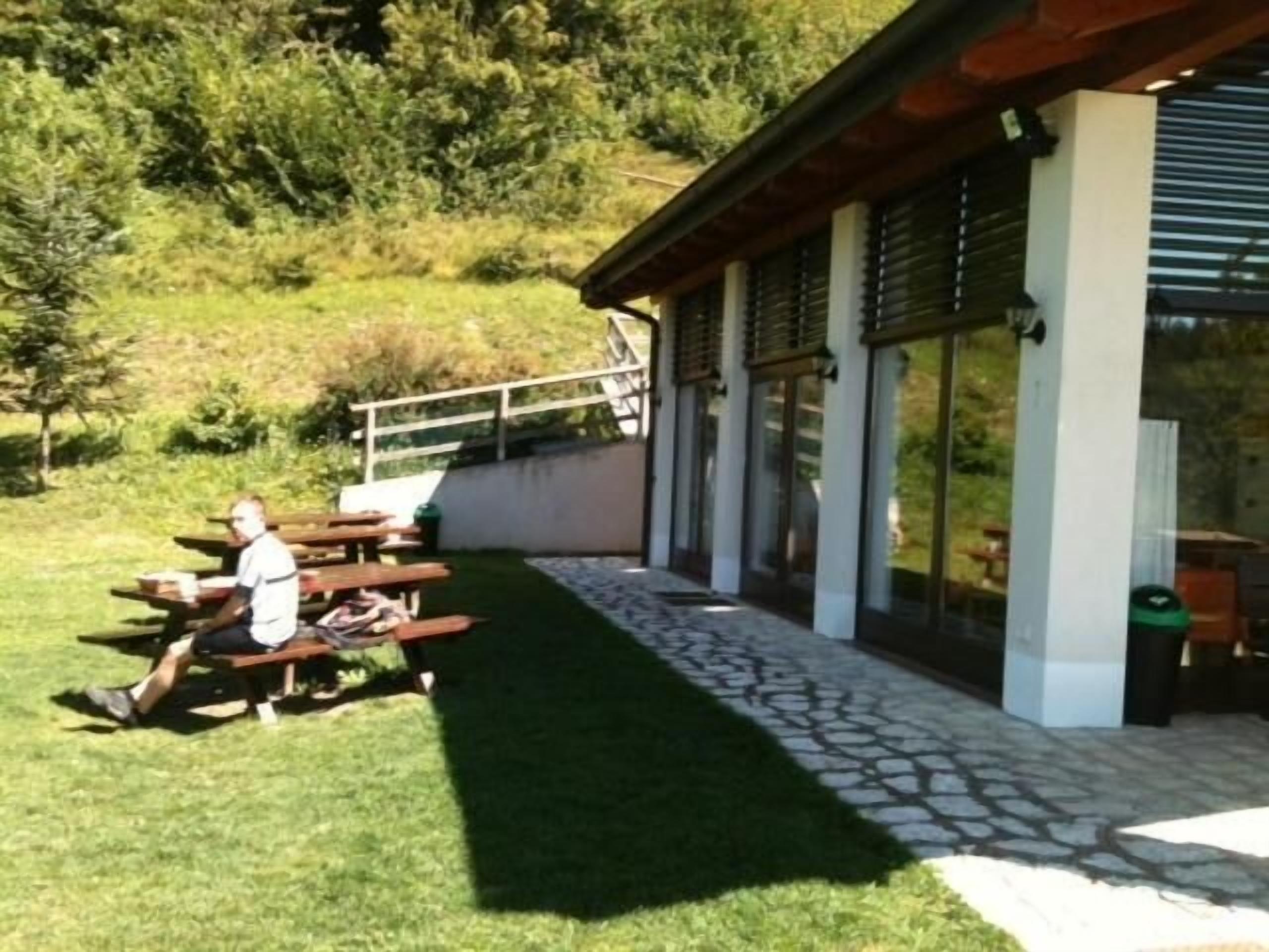 An outdoor patio area with wooden benches and a person sitting.