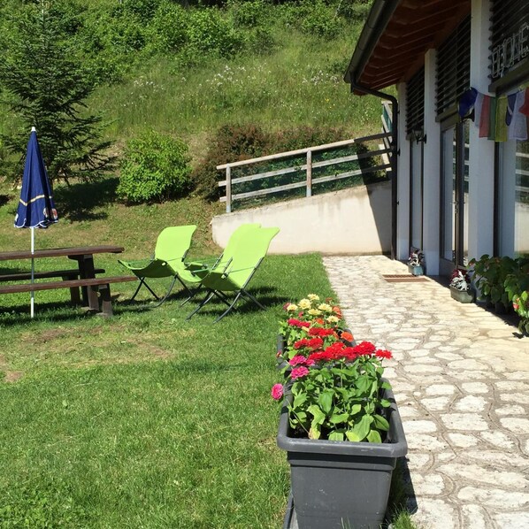 A patio area with green chairs, a picnic table, and a flower planter. - Malga Zanga (Arco)