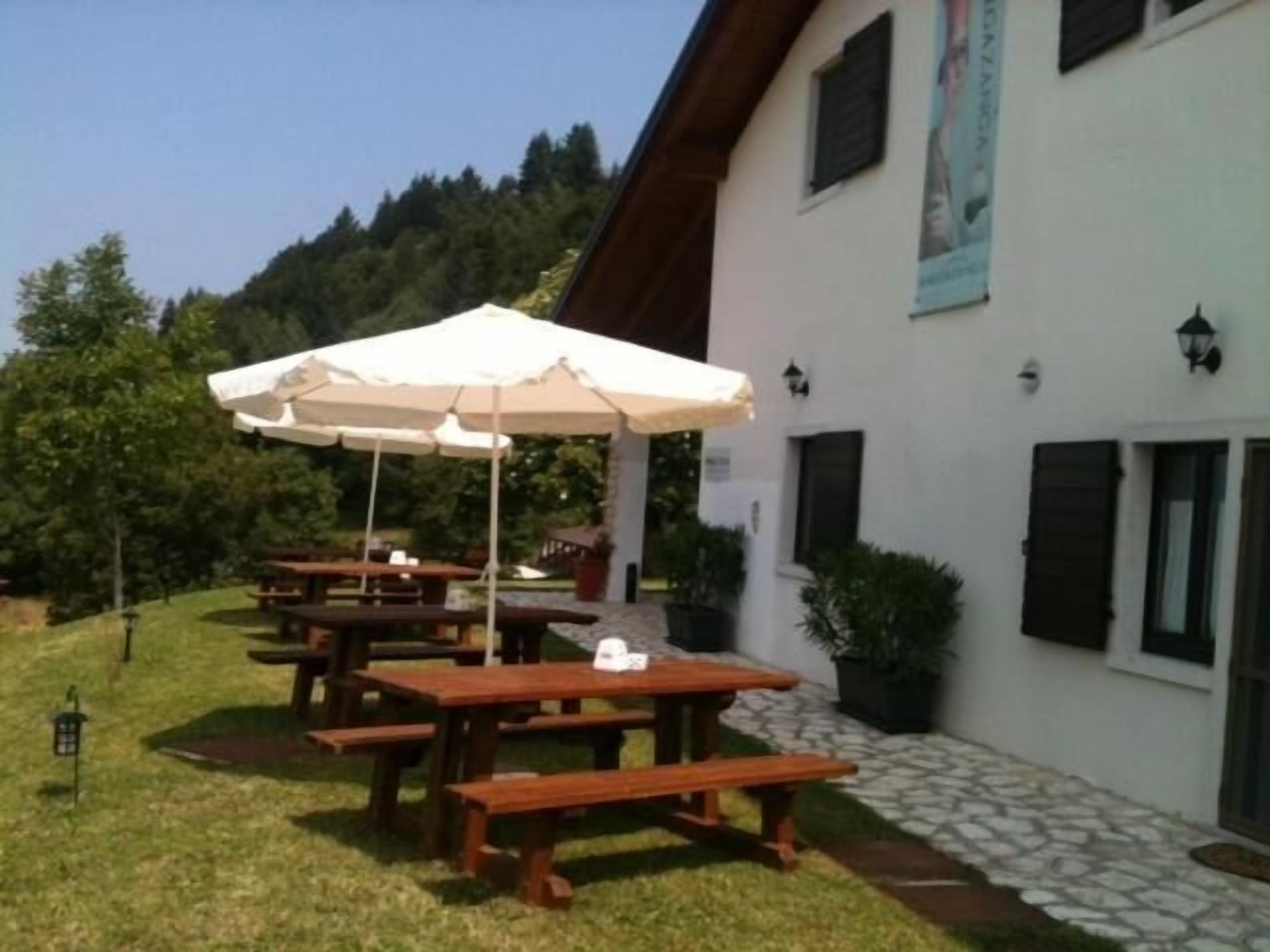 Un bâtiment doté de tables de pique-nique en bois à l’extérieur et d’un parasol blanc.