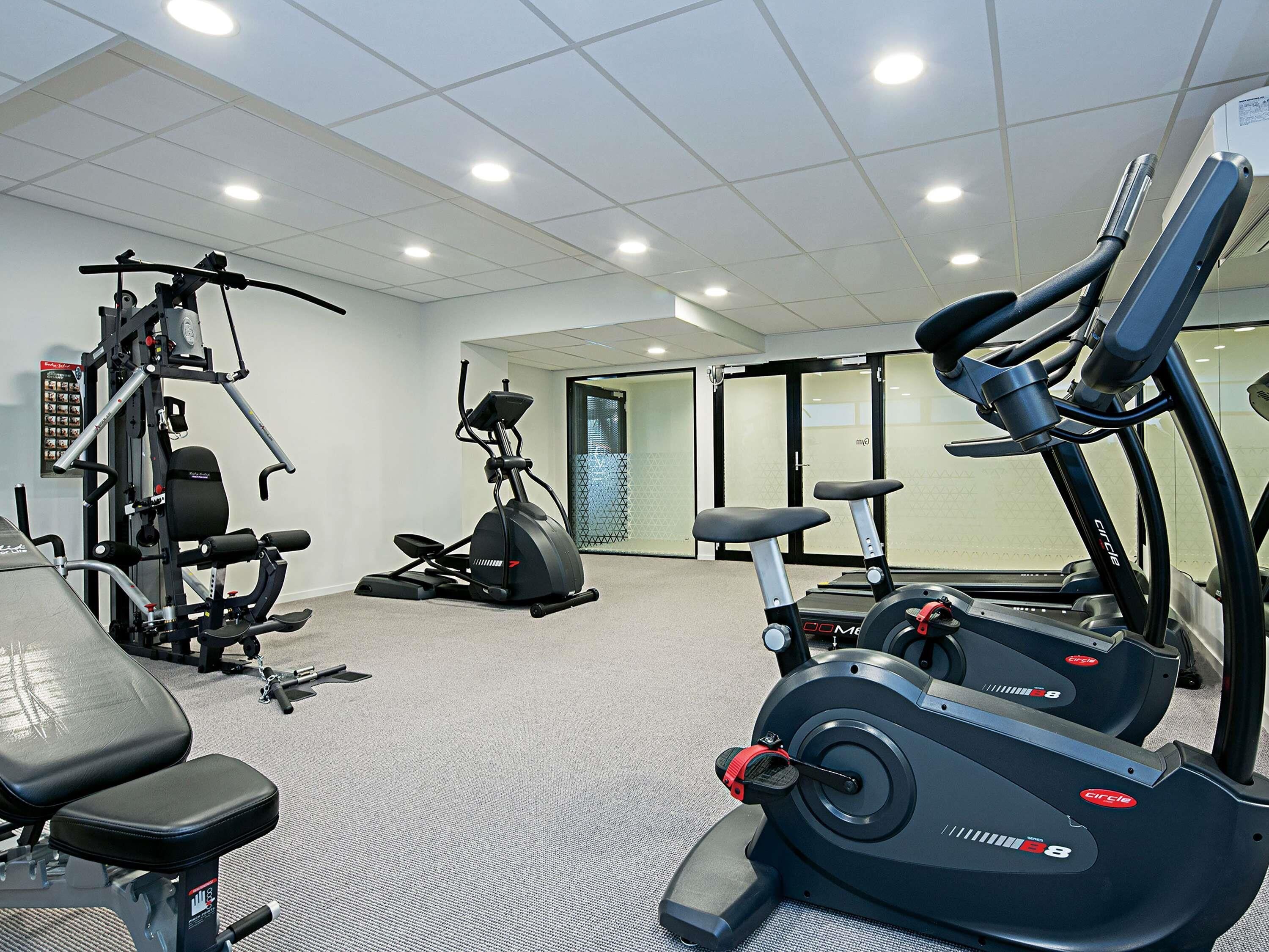 Un gimnasio con máquinas de cardio, máquinas de pesas y una banca.