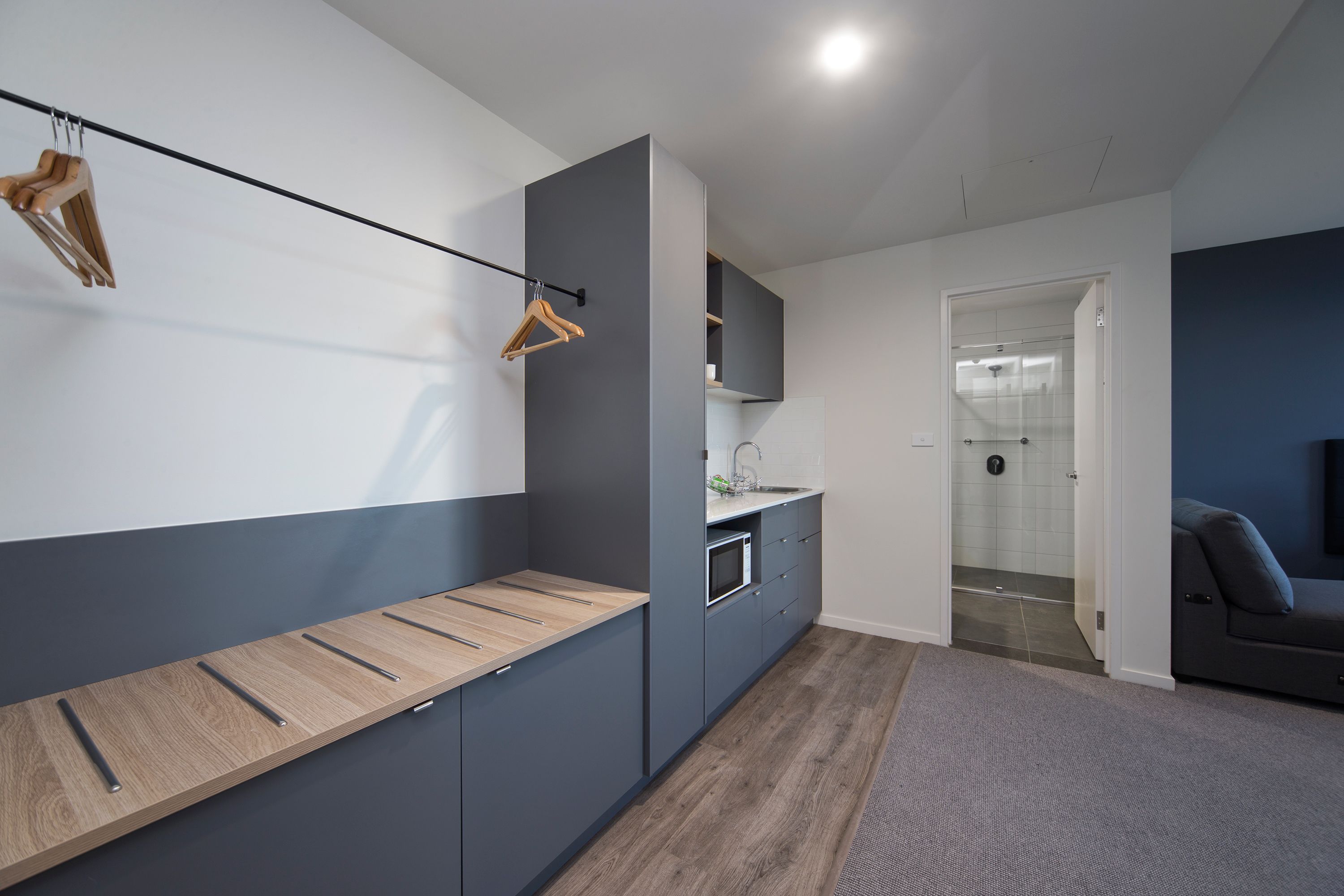 A modern kitchen with grey cabinets, a wooden countertop, and a hanging wooden hanger.