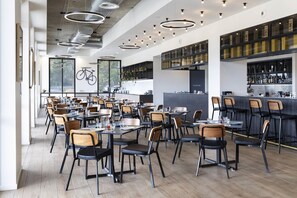 Enjoy a casual dining experience with tables for one or a group, set with basic tableware, and a self-service bar area.