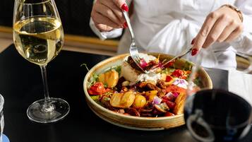 Une table à manger avec une assiette de nourriture, un verre de vin blanc et un verre de vin rouge.