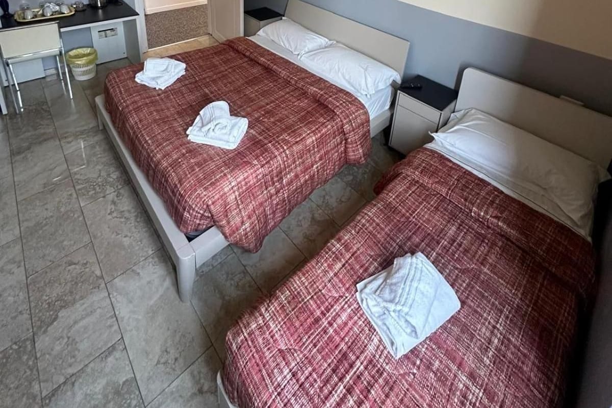 A hotel room with two beds, a desk, and a wardrobe.