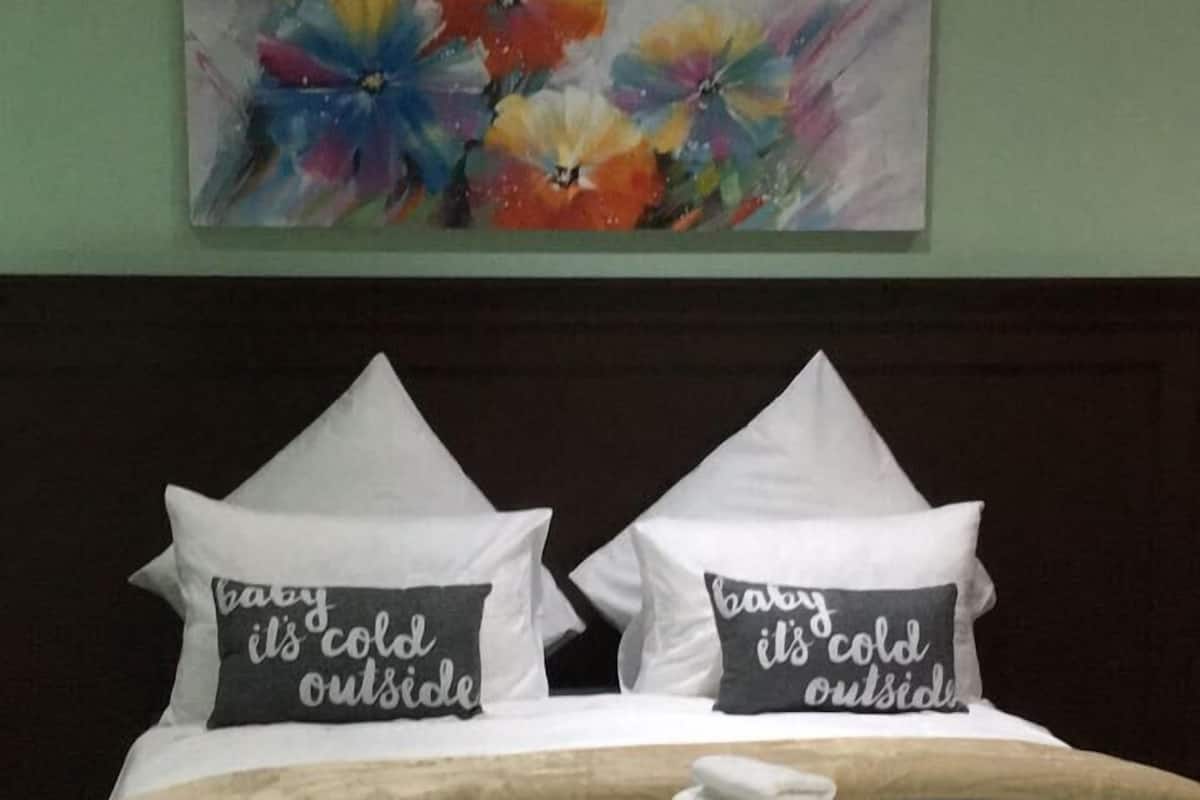 Een hotelkamer met een bed, kussens, een dekbed en een schilderij aan de muur.