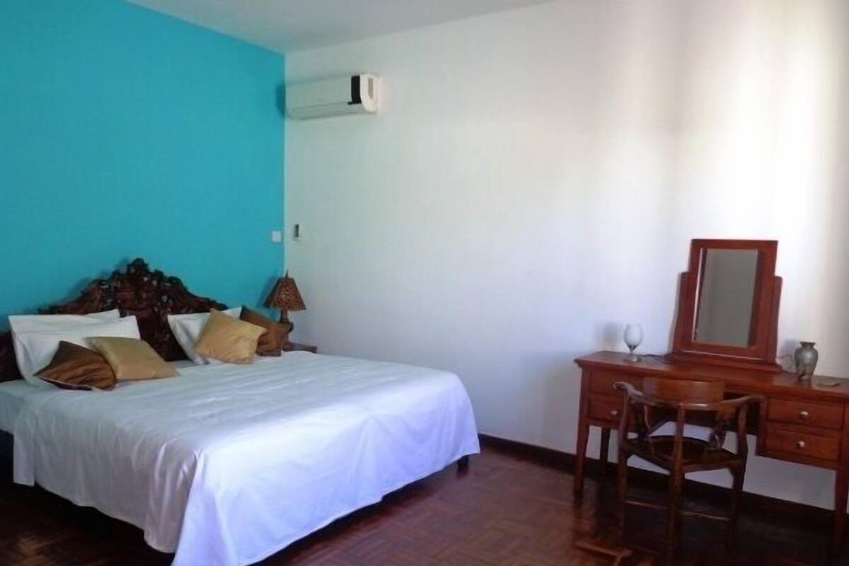 Une chambre à coucher avec un lit, une commode en bois et une chaise.