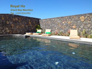 A pool area with stone walls and lounge chairs. - Royal Ho (Grand-Baie)