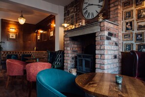 A cozy restaurant interior with brick walls, a fireplace, and leather seating. - Arthur's of Churchtown (Southport)