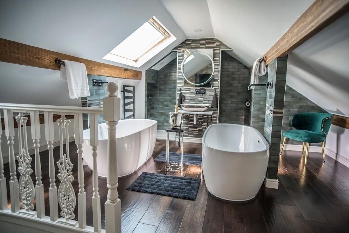 A modern bathroom with a freestanding bathtub, a large mirror, and a skylight.