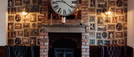 Una habitación acogedora con un gran reloj de pared, una chimenea y cuadros en las paredes.