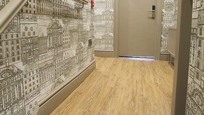 A hallway with a wooden floor and walls covered in a detailed cityscape mural. - Arthur's of Churchtown (Southport)