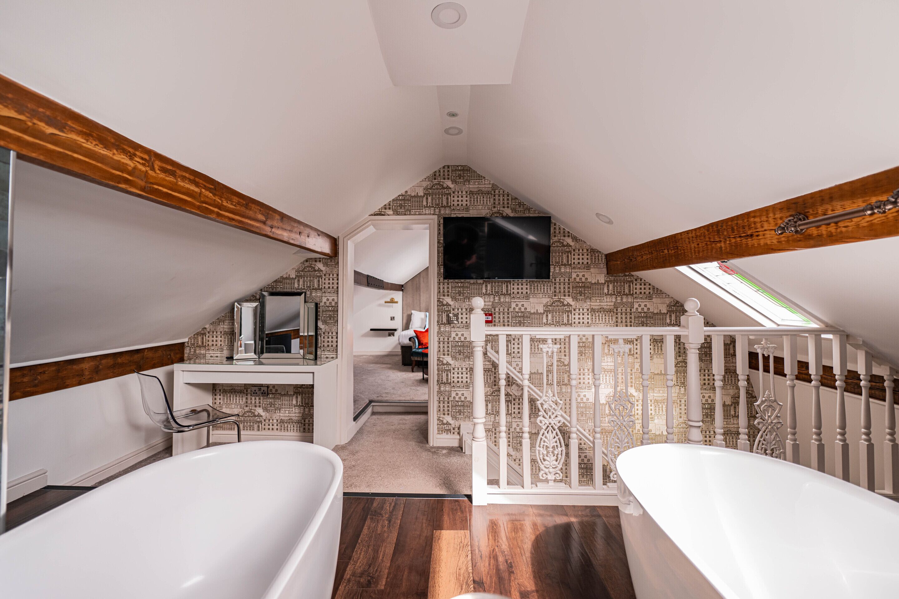 A spacious bathroom with two white tubs, a wooden ceiling, and a patterned wall.