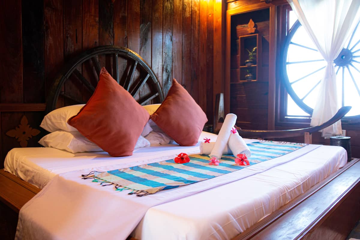 A neatly made bed with striped bedding, two pillows, and a decorative headboard.
