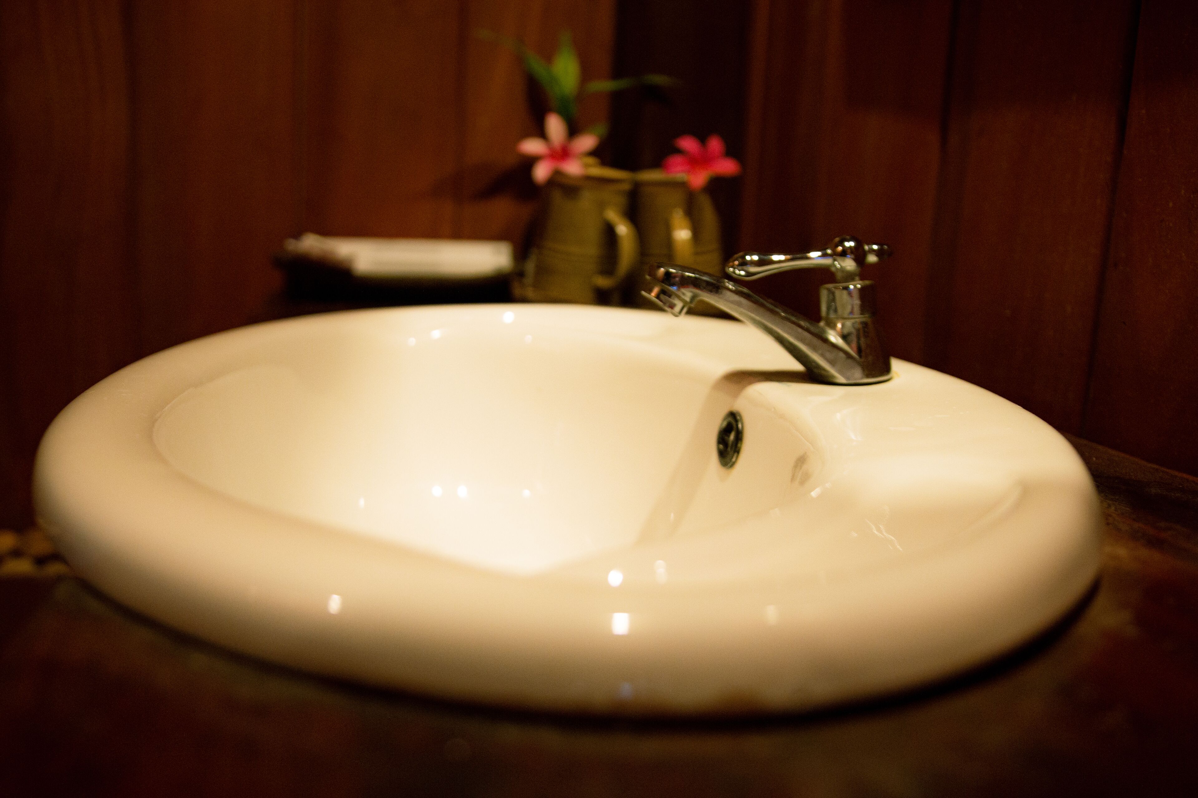 A white sink with a single faucet in a bathroom with wooden walls.