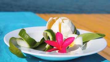A plate with a fruit and a flower on a table.