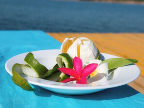 A plate with a fruit and a flower on a table. - Mekong Bird Resort (Stung Treng)