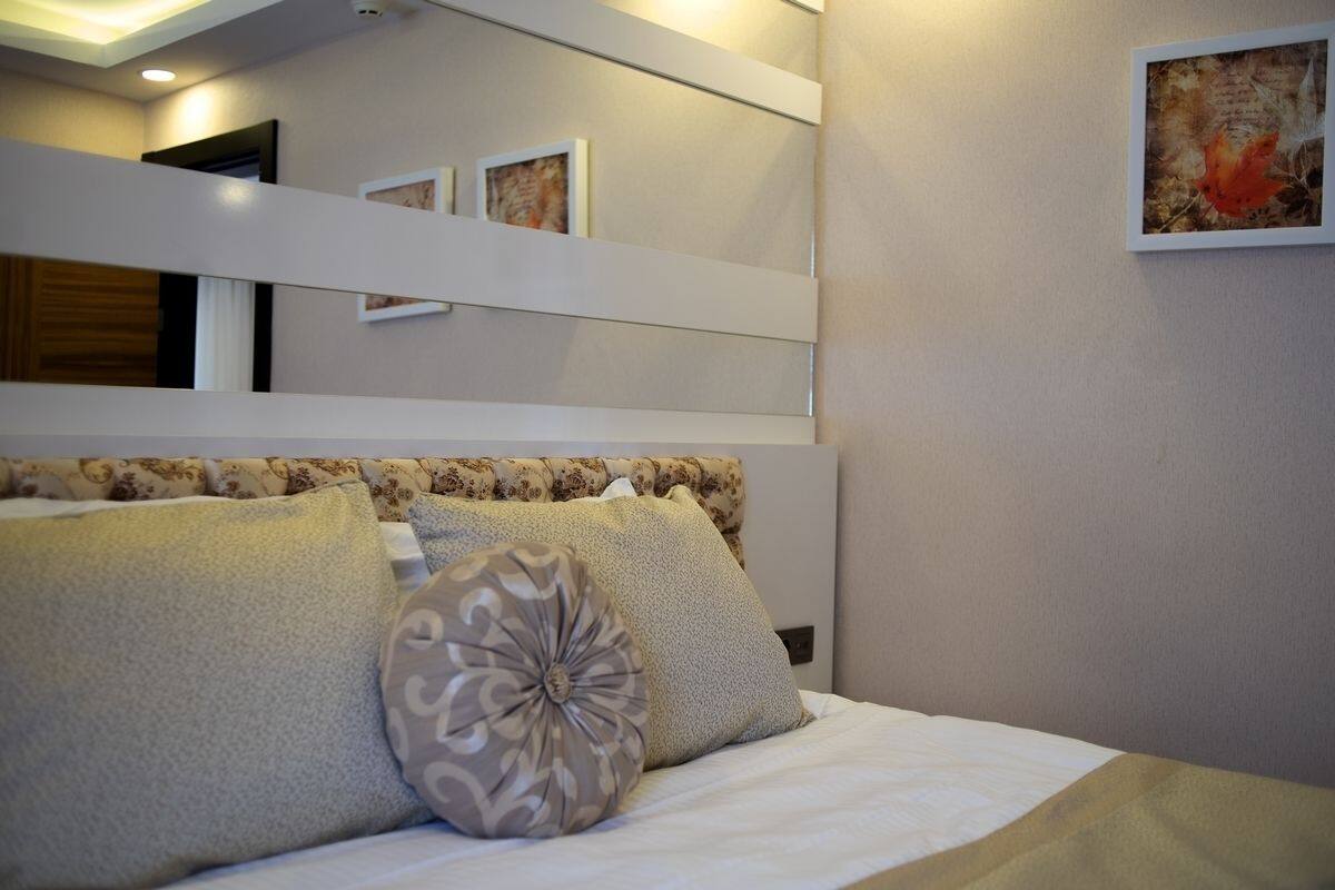 A bedroom with a bed, pillows, a headboard, and a wall-mounted artwork.