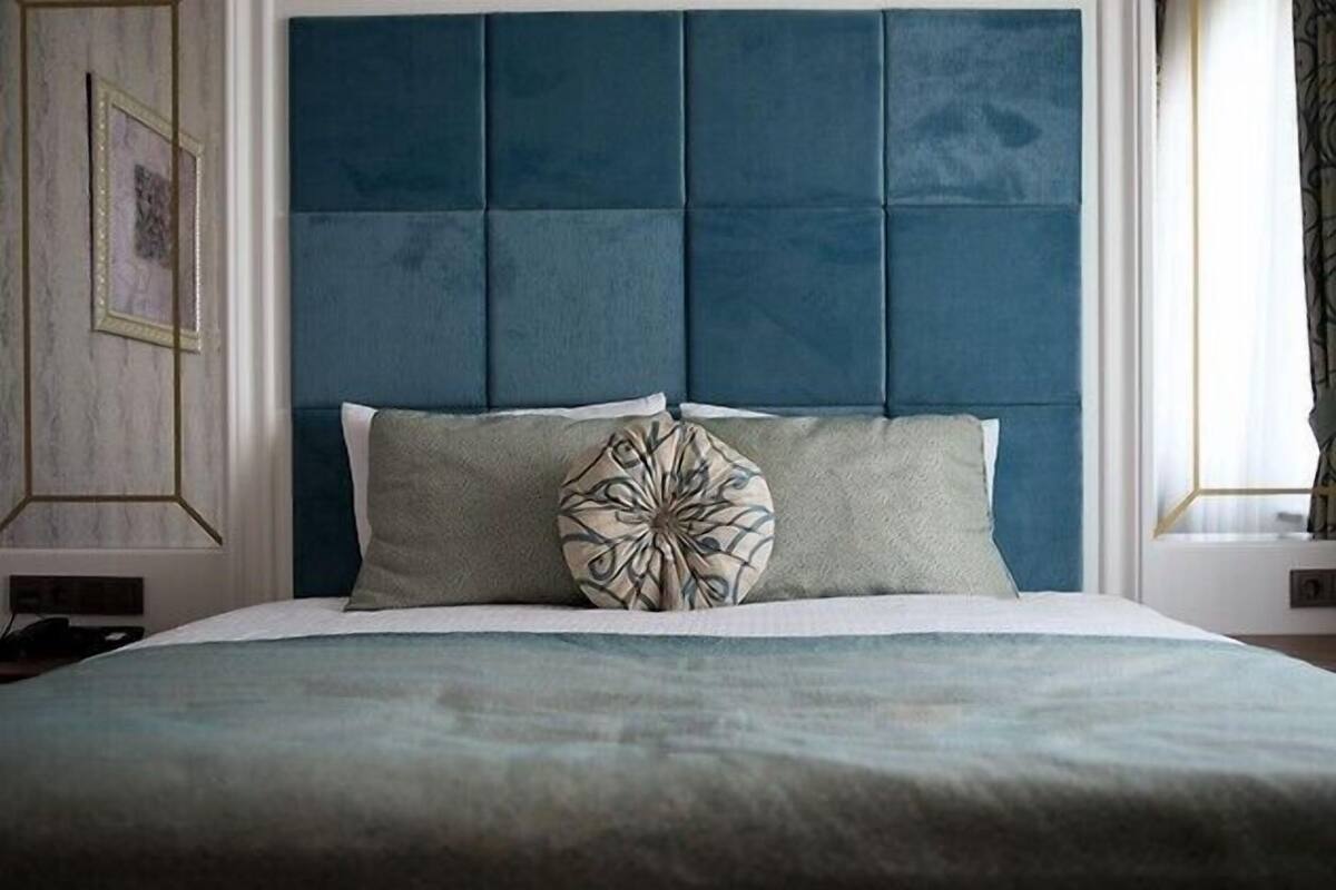 A bed with a blue headboard, a grey pillow, and a decorative pillow.