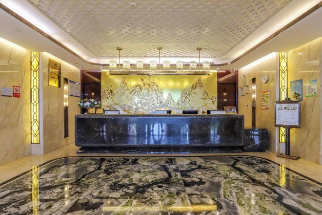 A hotel reception area with a marble floor, a reception desk, and a decorative wall.