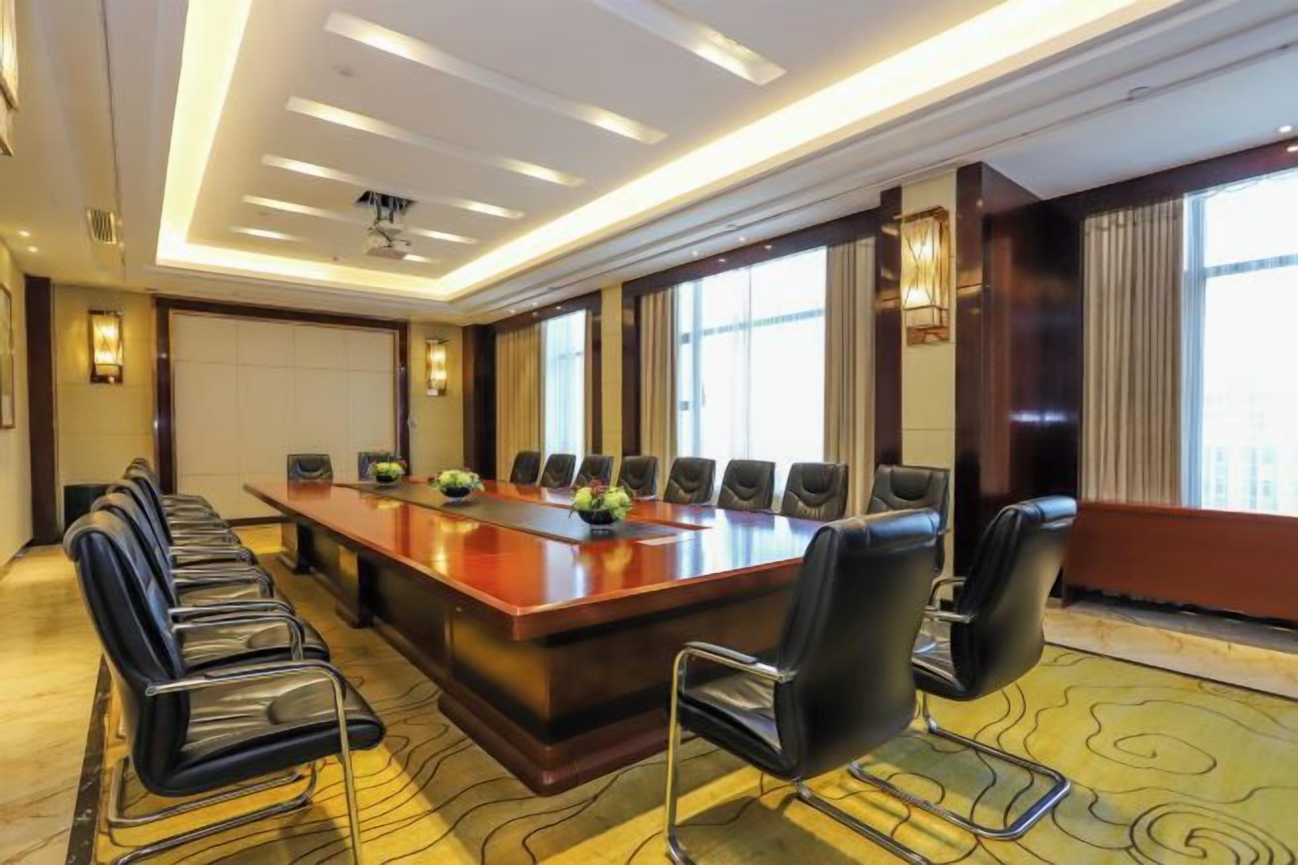 A conference room with a long table, multiple chairs, and large windows.