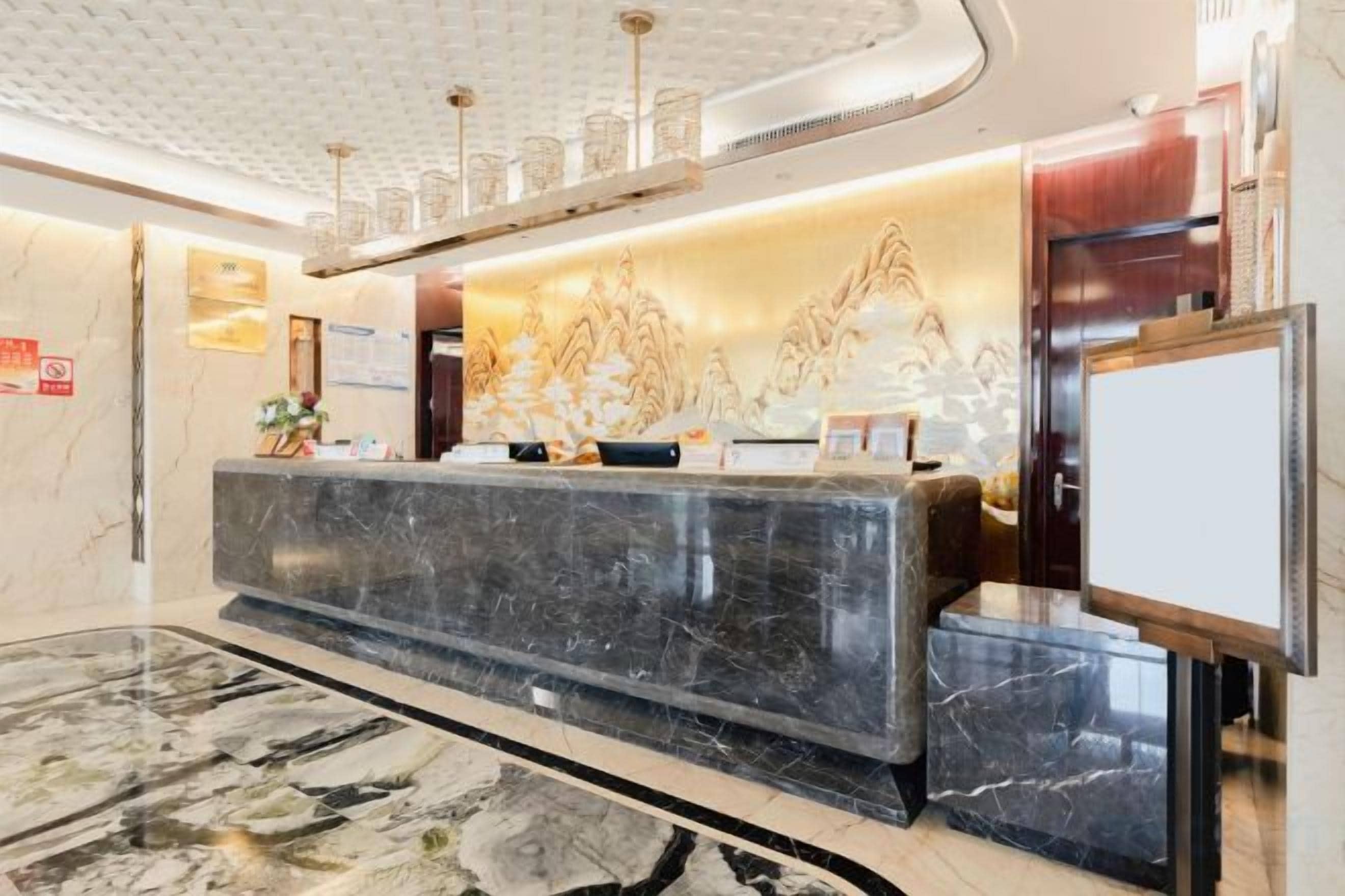 Ein Hotel-Empfangsbereich mit einer Marmor-Theke, einem Empfangsschalter und einem großen Wandbildschirm.