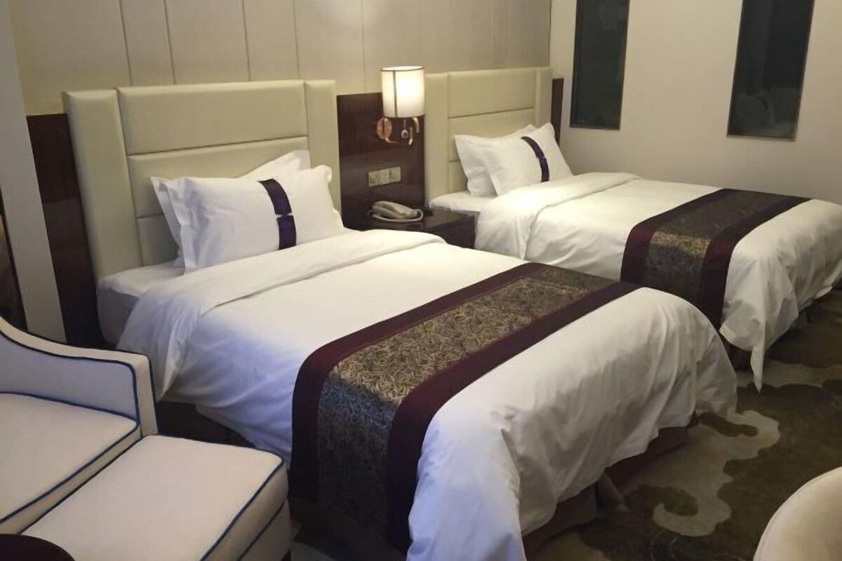 Ein Hotelzimmer mit zwei Betten, einem Nachttisch mit Lampe und einem Sessel.