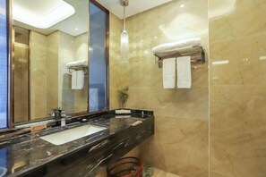 Ein modernes Badezimmer mit einem großen Spiegel, einer schwarzen Marmorarbeitsplatte und beige gefliesten Wänden.