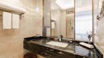 A modern bathroom with a black marble countertop, a large mirror, and a glass shower enclosure.