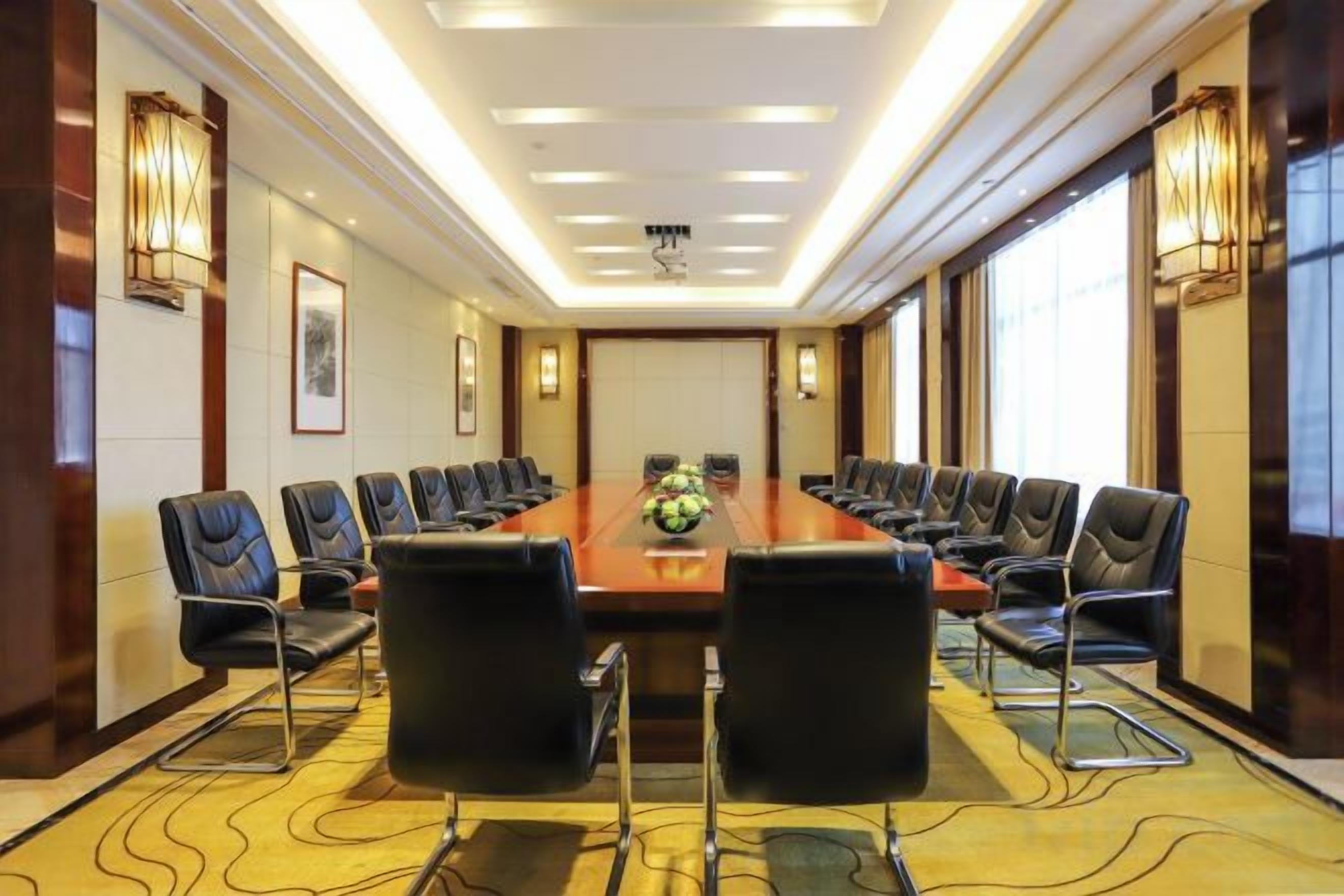 A conference room with a long table, multiple chairs, and a carpeted floor.