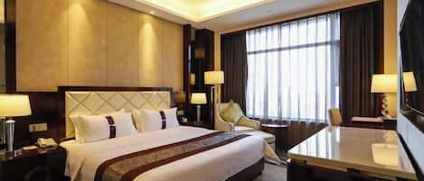 A hotel room with a large bed, bedside tables, a desk, and a TV.