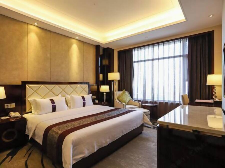 A hotel room with a large bed, bedside tables, a desk, and a TV.