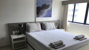 Une chambre d’hôtel moderne avec un grand lit, une table de chevet, une lampe de bureau et une fenêtre avec des rideaux.