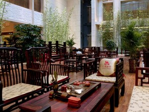 A traditional-style restaurant with wooden furniture and a central table with teapots and cups. - Tang Dynasty West Market Hotel (Xi'an)