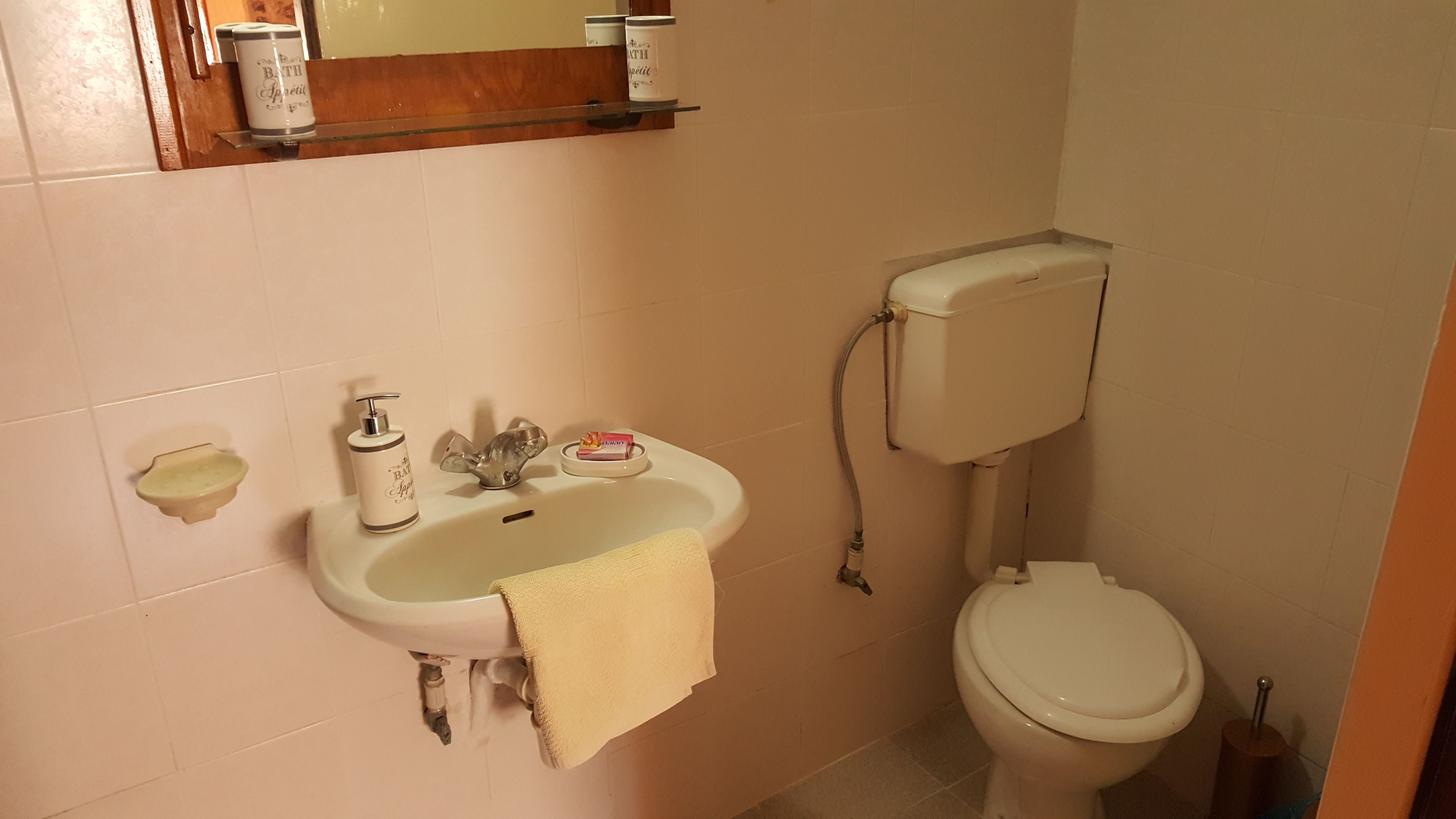 A bathroom with a sink, toilet, and a mirror above the sink.