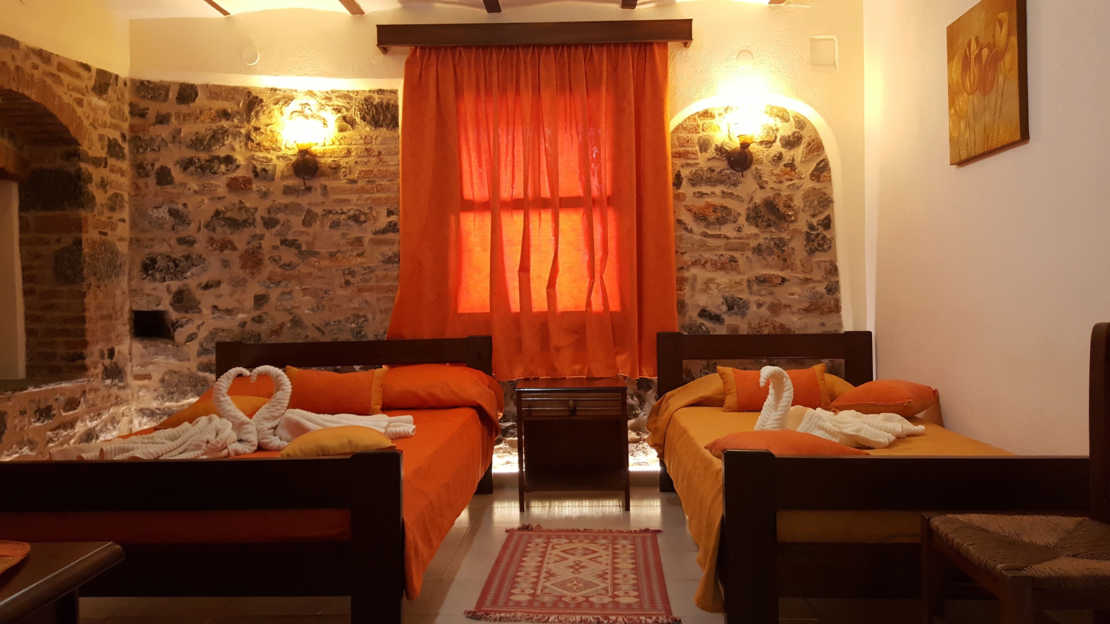 Una habitación con dos camas, una mesita, una silla, una alfombra y un cuadro en la pared.