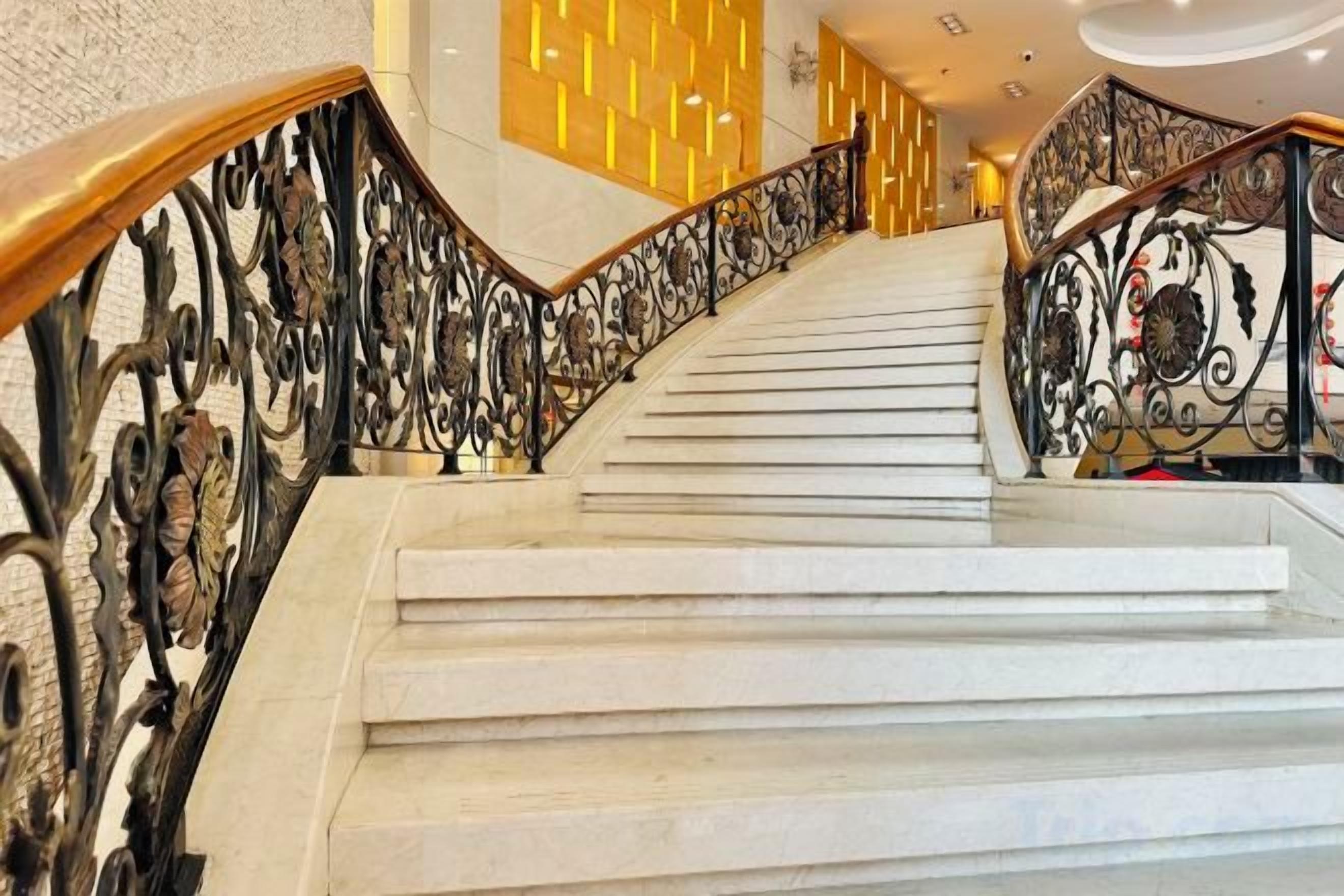 A staircase with ornate metal railings and a polished stone floor.