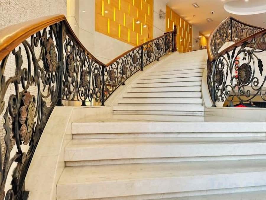 A staircase with ornate metal railings and a polished stone floor.