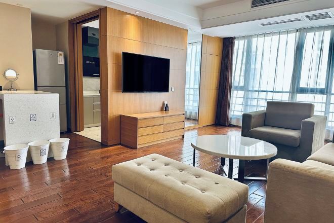 Una habitación de hotel moderna con una televisión de pantalla plana, un sofá, una mesa redonda de centro y una pared decorativa de madera.