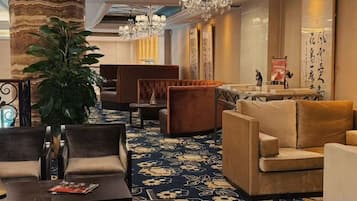 A hotel lobby with seating areas, a large plant, and a chandelier.