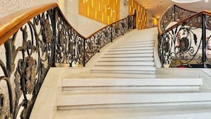 A marble staircase with ornate metal railings and a modern wall with vertical light panels. - Eaself Hotel (Beijing)