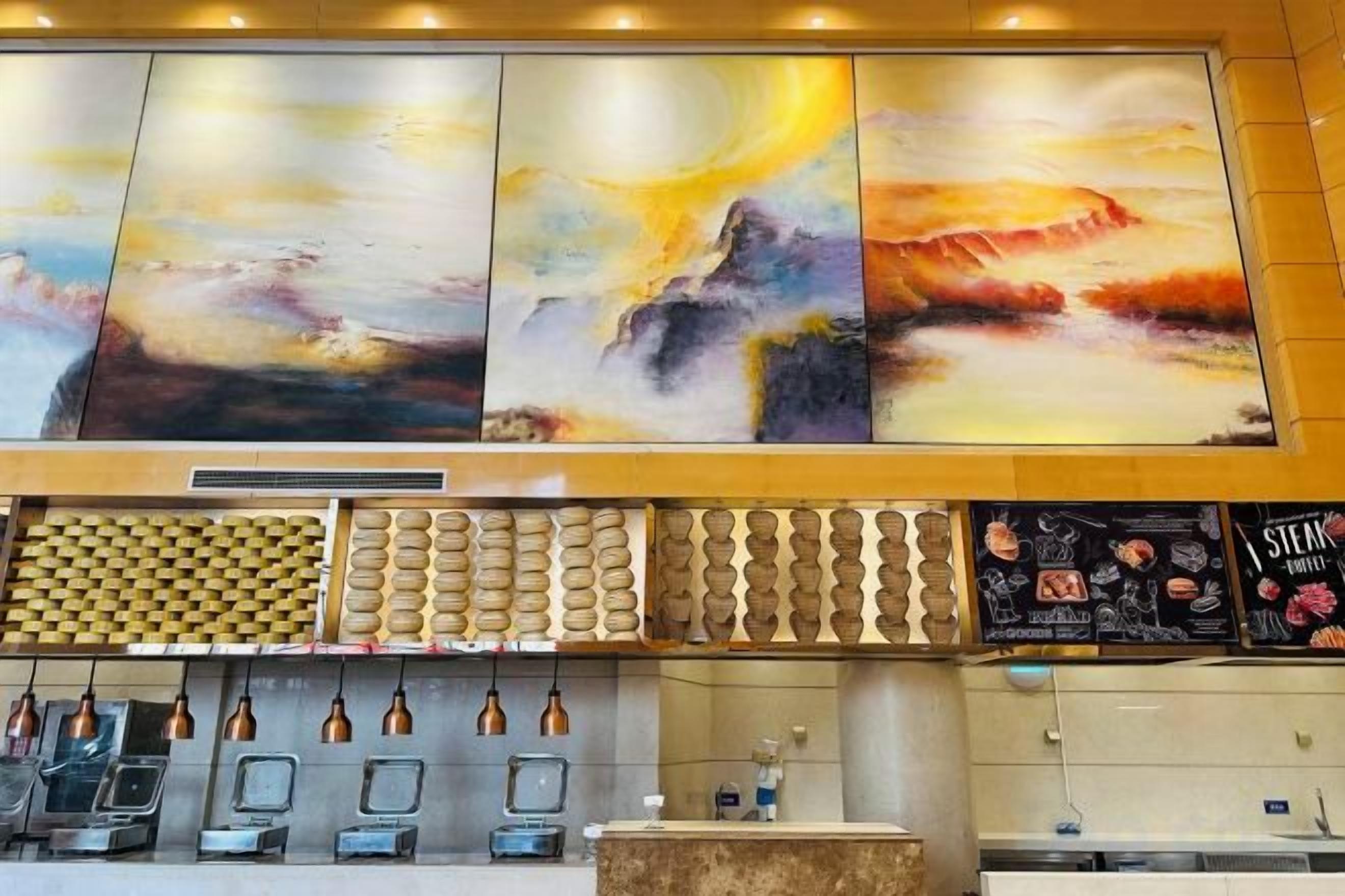 A hotel lobby with a large abstract painting, a patterned wall, a reception desk, and a menu board.