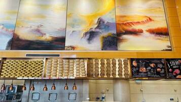 A hotel lobby with a large abstract painting, a patterned wall, a reception desk, and a menu board.