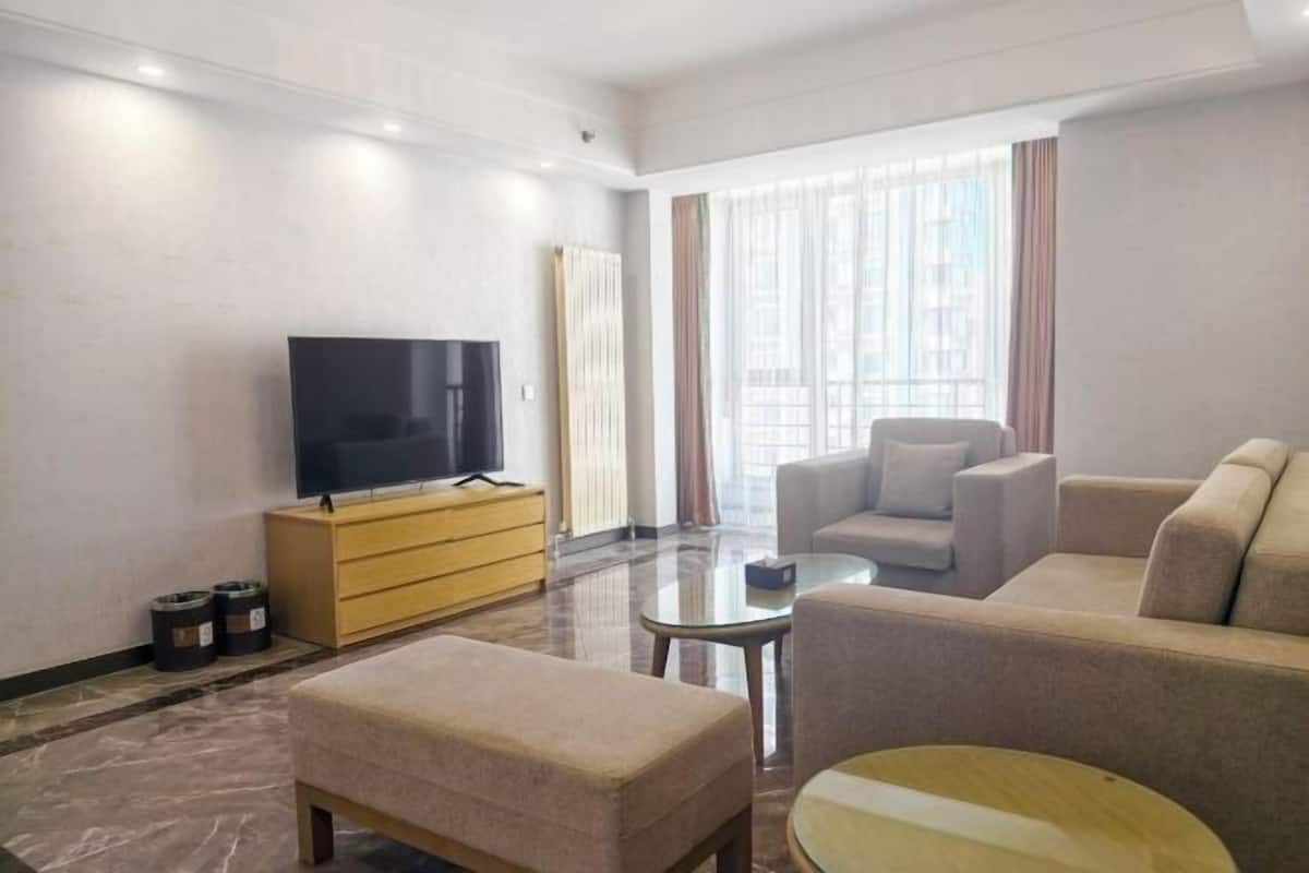 A modern living room with a flat-screen TV, a sofa, a coffee table, and a glass-top table.