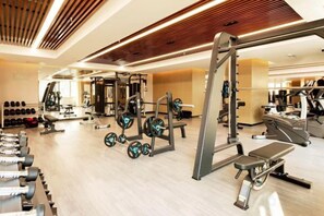 Une salle de sport équipée de divers appareils d’exercice, notamment des haltères, des appareils de musculation et des appareils de cardio.