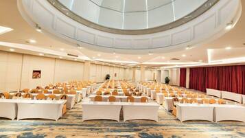 A large conference room with rows of tables and chairs, a high ceiling with a skylight, and a carpeted floor.