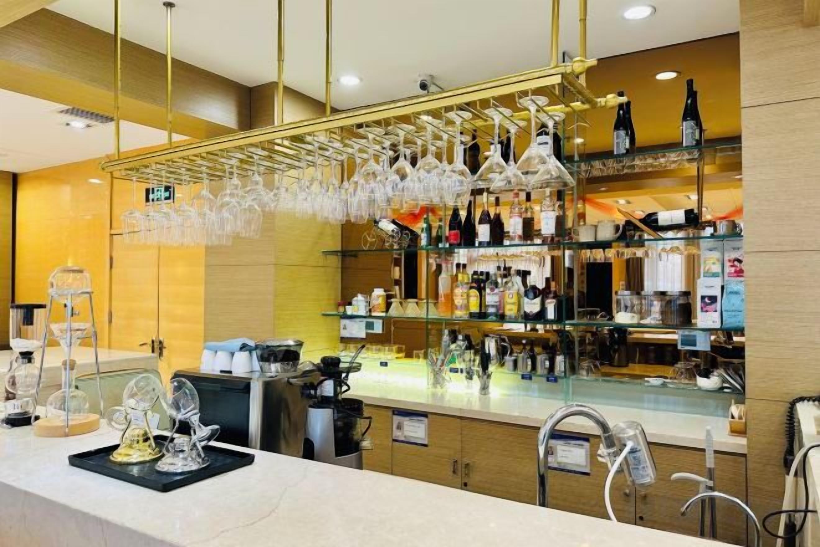 A bar area with a counter, hanging glasses, and shelves with bottles.