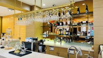 A bar area with a counter, hanging glasses, and shelves with bottles.