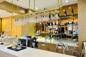 A bar area with a counter, hanging glasses, and shelves with bottles. - Eaself Hotel (Beijing)