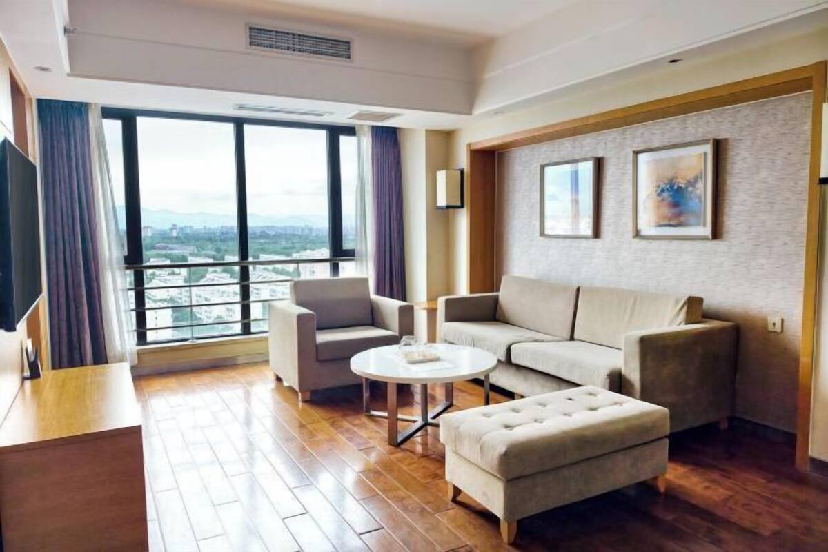 A modern living room with a sofa, armchairs, a coffee table, and a TV.