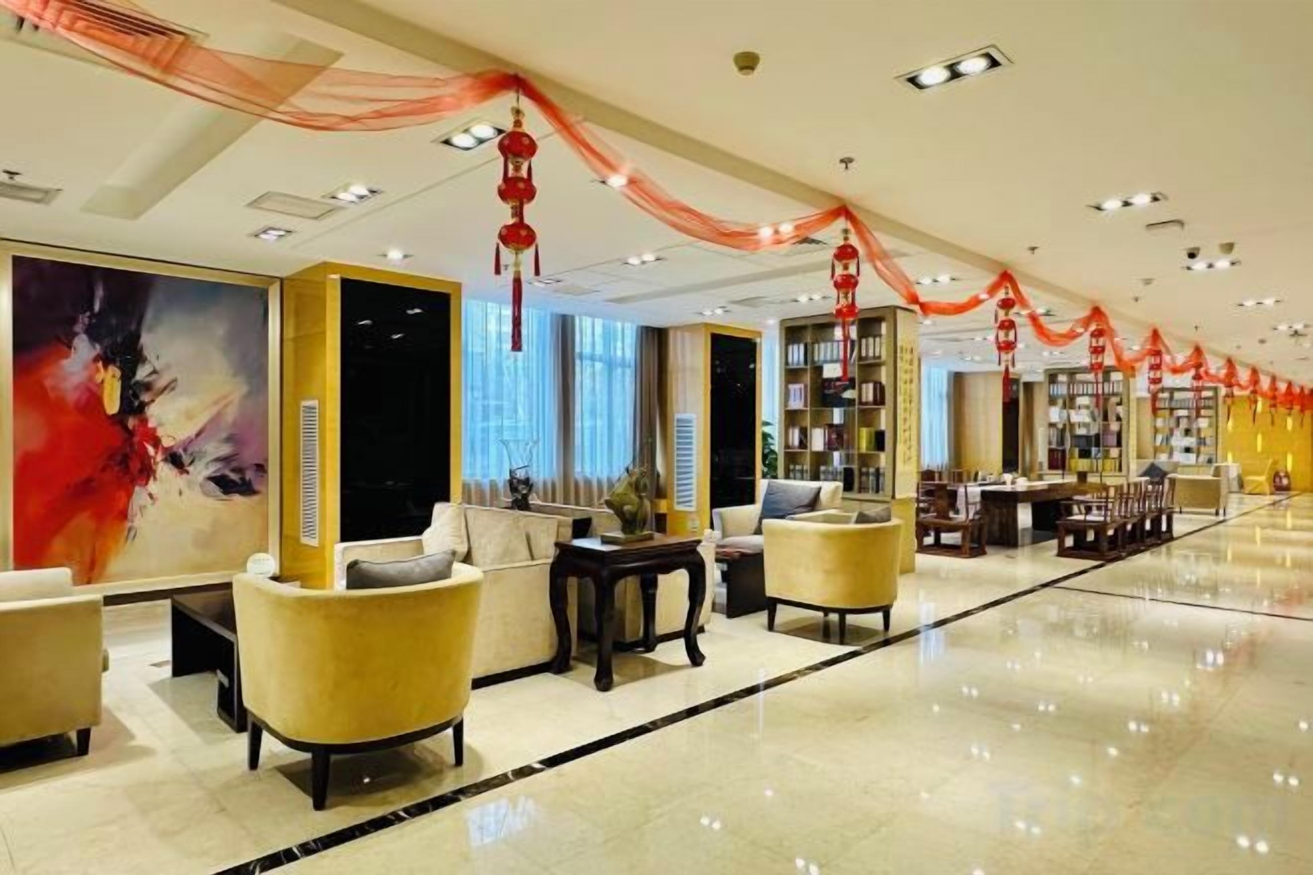 A hotel lobby with seating areas, a reception desk, and a bookshelf.